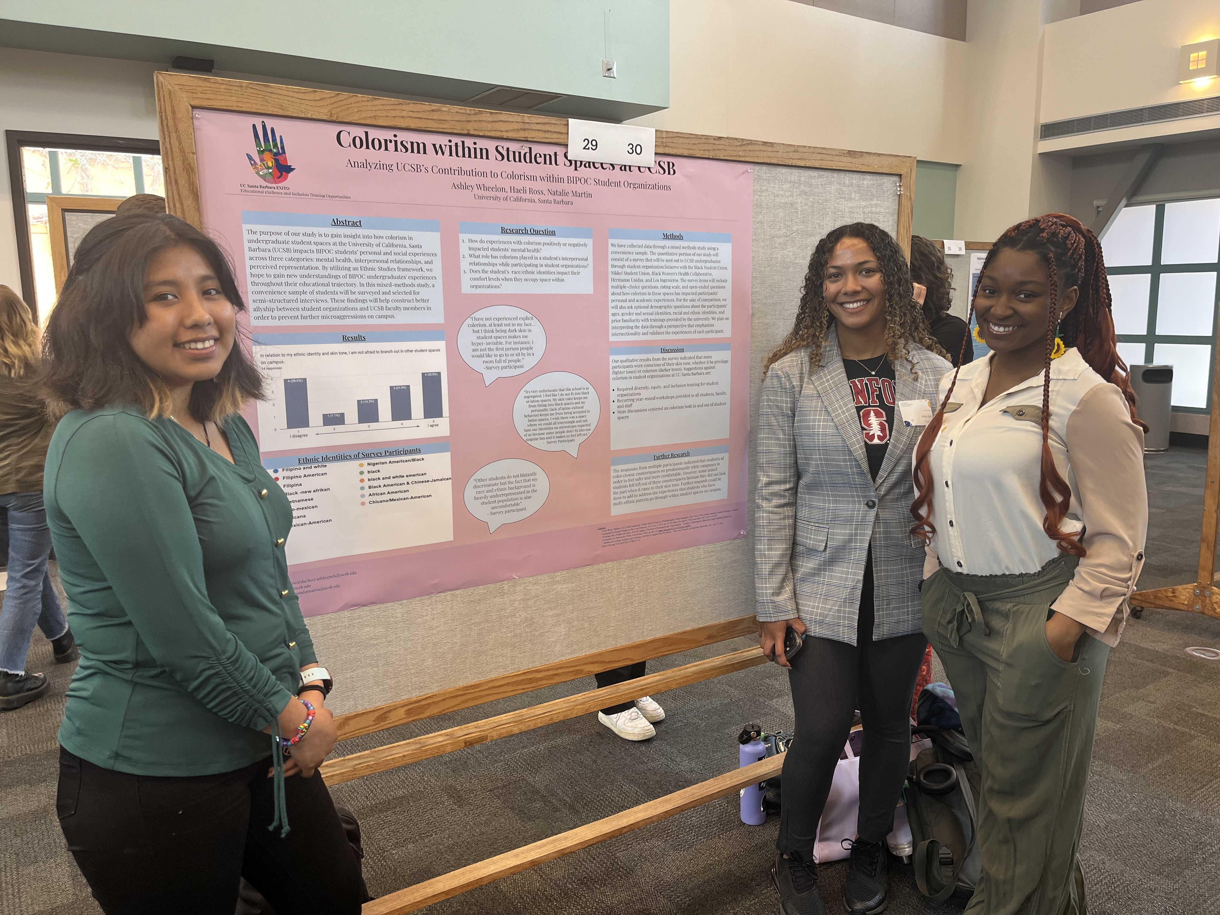 "Three students stand around poster board displaying their research project"