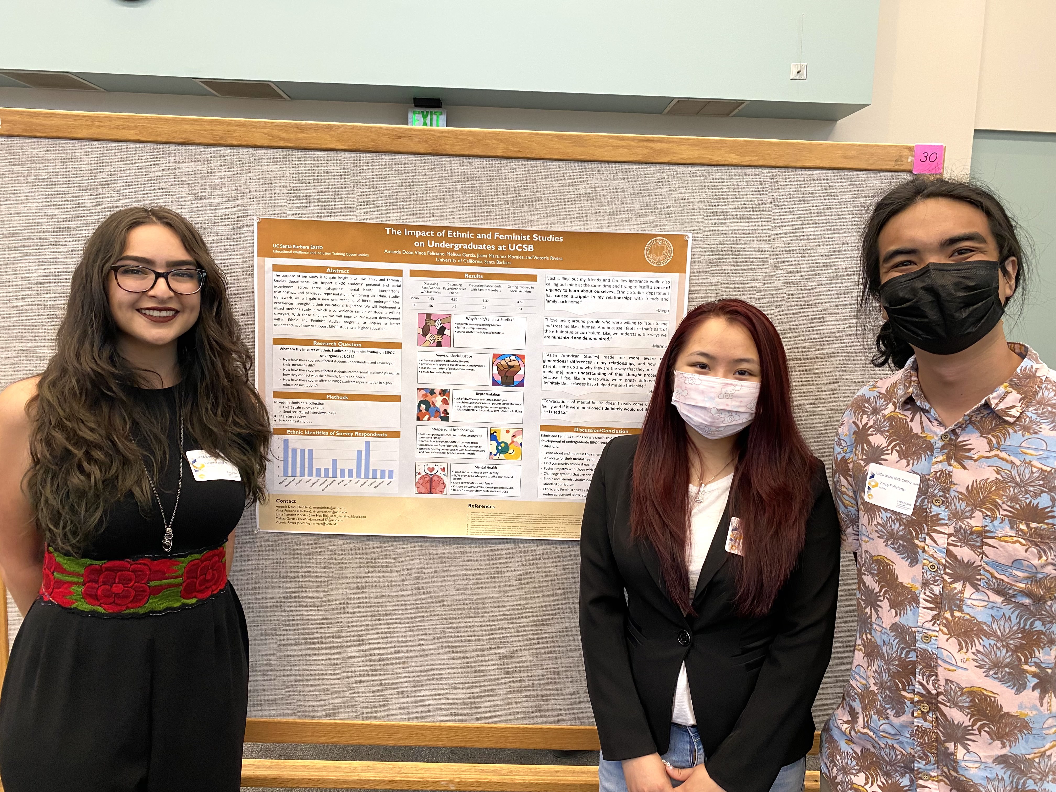 Three Students stand next to poster board presentation