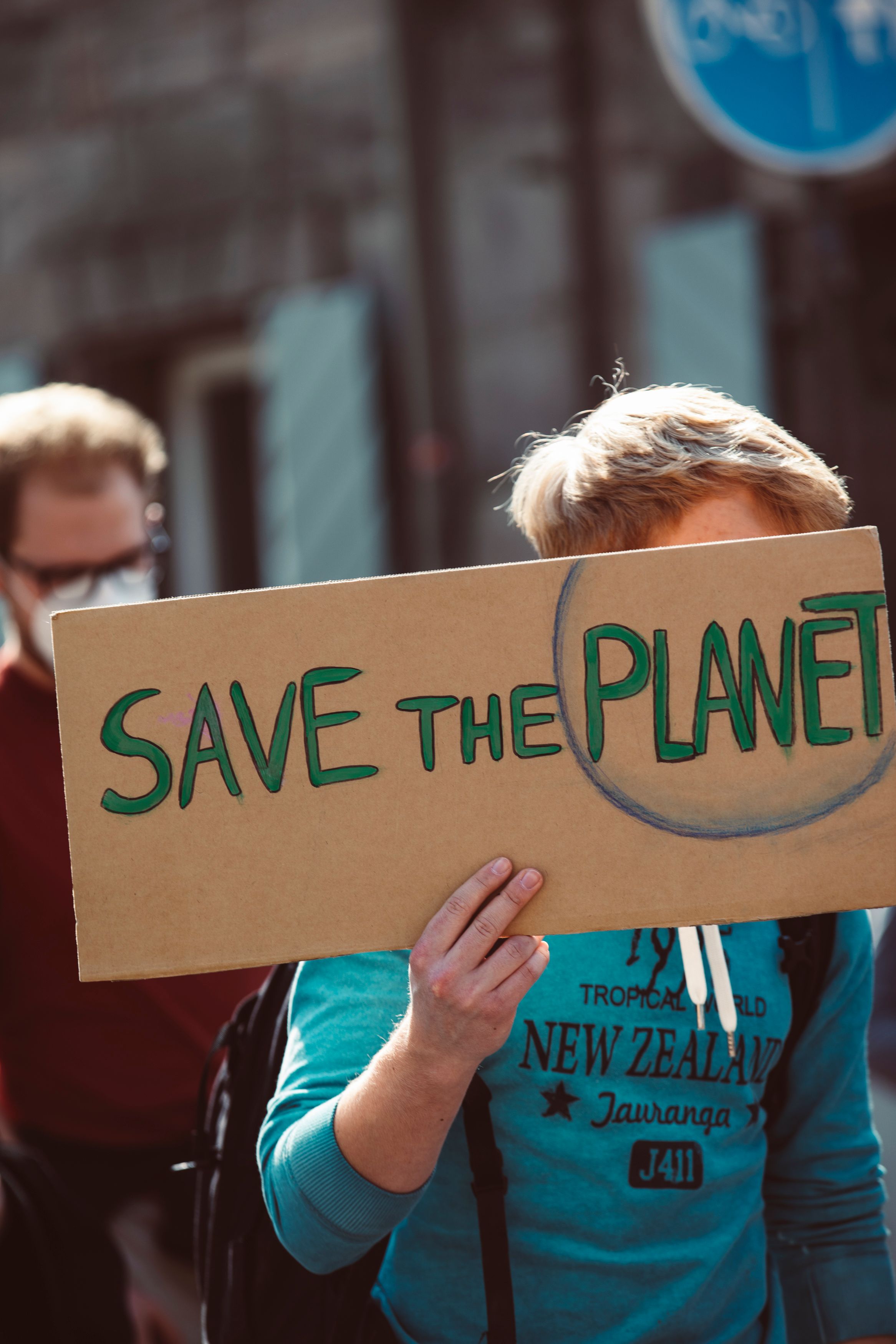 Young man holds a cardboard sign saying 'Save the Planet'