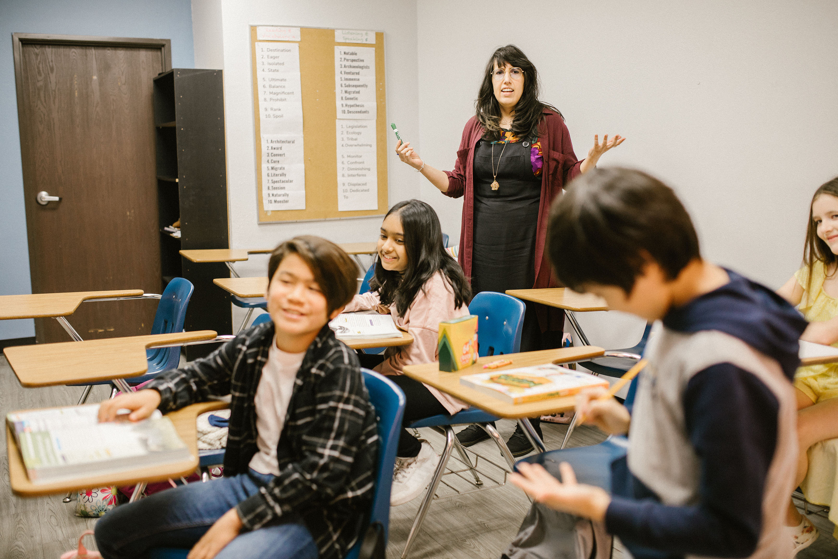 Middle school class with teacher standing and talking in the back 